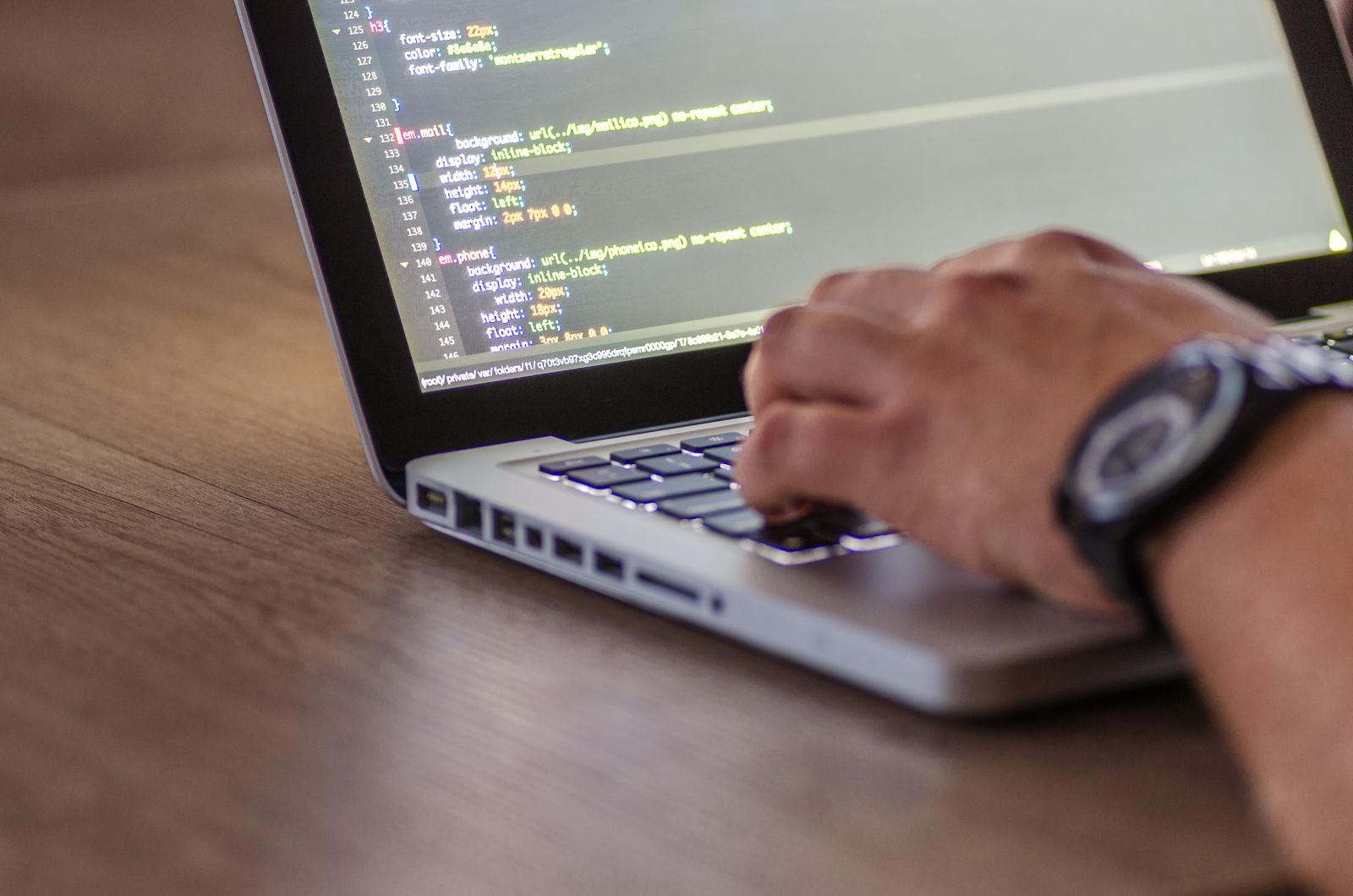 Hands typing code on a laptop